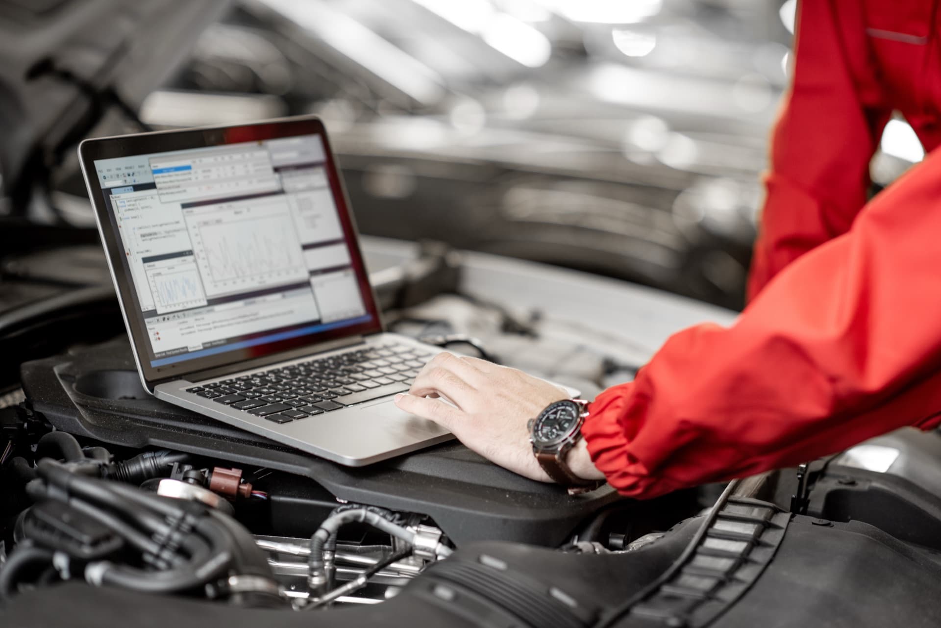 Mécanicien utilisant un logiciel DMS garage sur ordinateur portable dans un atelier automobile