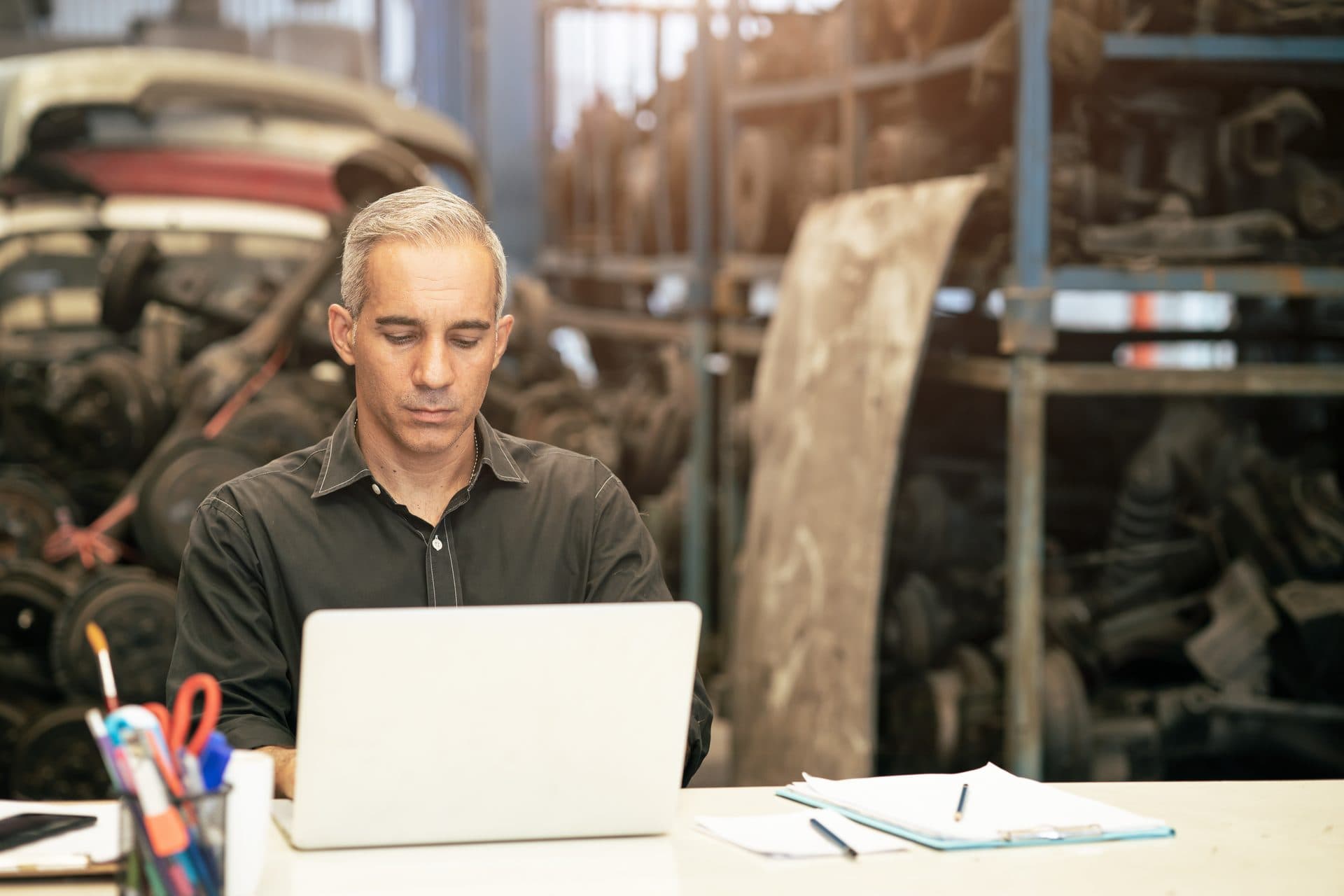 Gérant de garage préparant sa clôture comptable sur ordinateur, au bureau de l'atelier